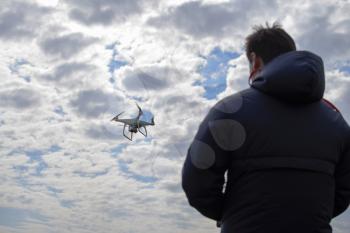 A man with a remote control in his hands. Controlling the flight of the drone against the sky. Phantom