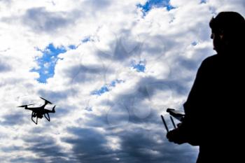 A man with a remote control in his hands. Controlling the flight of the drone against the sky. Phantom