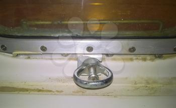 The fastening element is the lock on the porthole window. A window in the ship.