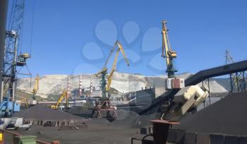 Cargo industrial port, port cranes. Loading of anthracite. Transportation of coal. Heap of coal.