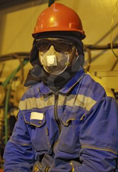 The worker in overalls and a respirator. Protective attire of technical workers.