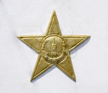 Yellow five-pointed star on a white wall. A symbol of victory