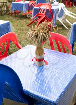 Still life on the tables of summer cafe. A bouquet of wheat spikes and a poppy flower.