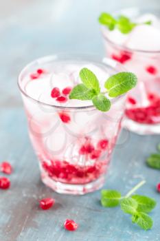 Infused water made of fresh pomegranate and mineral water with ice, cold refreshing and detox drink