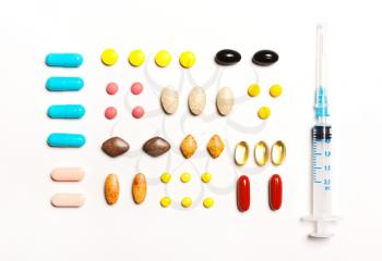  multi-colored tablets and prick, vitamins, dietary supplements in a row on a white background. View from above, flat