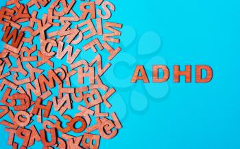 Word ADHD from wooden letters on a blue background. attention deficit hyperactivity disorder handwritten