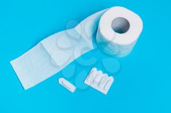 Medical suppository and toilet paper on a blue background, for the treatment of hemorrhoids, vaginal candidiasis