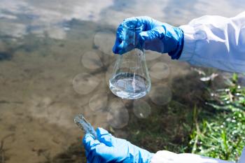 Analysis, water sample from the river, lake. A gloved hand collects water in a test tube. The concept of ecology, environmental pollution