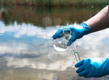 analysis of water from the river for pollution. Hand in a blue glove holds a test tube. The concept of environmental pollution, ecology