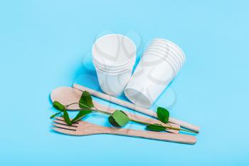 Organic fork, spoon, wooden tube, paper cups on a blue background. The concept of recycling, eco, planet conservation, zero waste