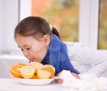 Little girl tries to taste a slice of orange