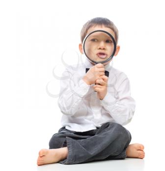 Cute little boy is looking through magnifier, isolated over white