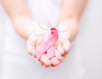 healthcare and medicine concept - girl hands holding pink breast cancer awareness ribbon