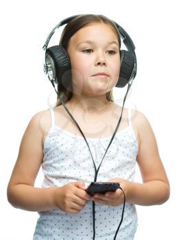 Cute little girl is enjoying music using headphones, isolated over white