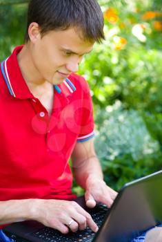 Young man is playing on laptop, outdoor shoot