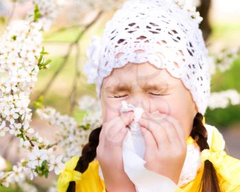 Spring portrait of a little girl is blowing her nose