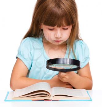 Cute little girl is looking at big paper sheet through magnifier, isolated over white