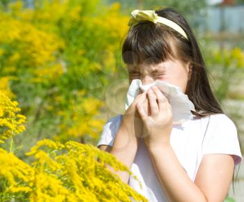Girl is blowing her nose, allergic to bloom flowers