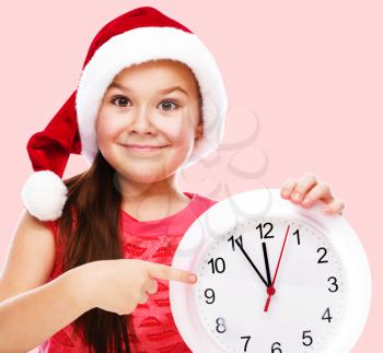 Christmas, winter, time and people concept - girl in santa helper hat with clock