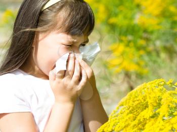 Girl is blowing her nose, allergic to bloom flowers