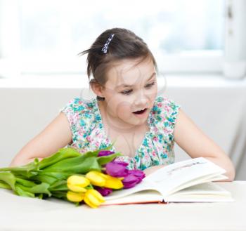 Portrait of the girl with flowers reading book. Spring holiday concept