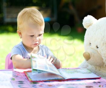 Little girl is reading a story for her teddy bears