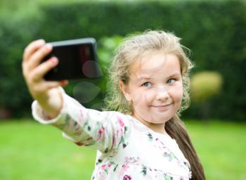 Cute happy girl makes self-portrait on the smartphone