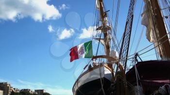 Italian Nautical flag with emblem of four Maritime Republics, Venice, Genoa, Pisa and Amalfi flag flutters in the wind. Vintage antique Italian sailing ship in port of city Ancona