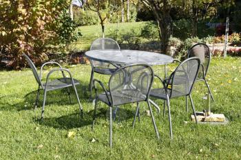 Vintage wrought iron table and chairs for picnic in Italian garden. Little summer restaurant.