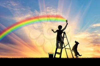 Child paints a rainbow in the sky at sunset with the dog