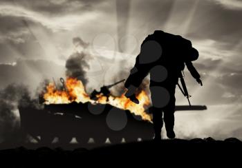 Concept of war and conflict. Soldier carries a wounded soldier on a background of a burning tank