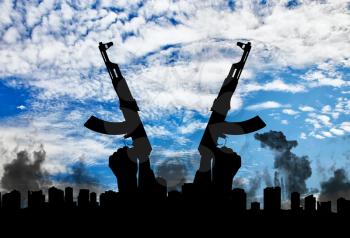 Terrorist concept. Weapons in the hands of terrorist, against the background of the city in smoke