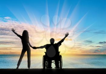 Happy disabled person in wheelchair holding hand girlfriend by sea day. Concept happy disabled and family