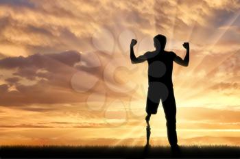 Disabled person with prosthetic leg standing on hill and raise hands up on sunset. Concept disabled