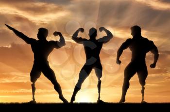 Invalids bodybuilders with prosthetic leg to stand in poses on sunset background. Concept handicapped and sport