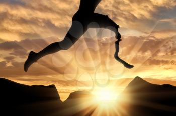 Disabled athlete with prosthetic leg jumping over stones on background sunset. Concept disability and sport