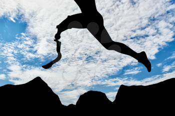 Disabled athlete with prosthetic leg jumping over rocks on background of sky. Concept disability and sport