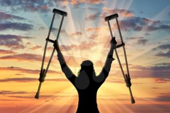 Happy disabled person with raised hands crutches sunset. Concept happy disabled