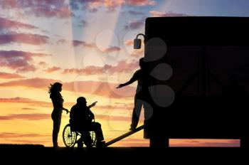 Disabled person in wheelchair to help climb the ramp in bus sunset. Concept help disabilities