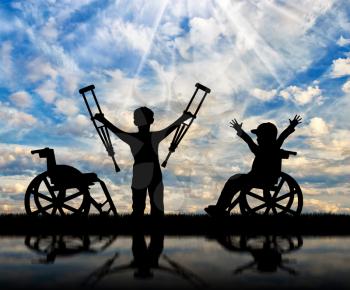 Boy in wheelchair and disabled boy standing with crutches near sea and reflection. Concept disabled child
