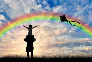 Young dad holding a child on his shoulders on a rainbow background, and they launch a kite. Concept family