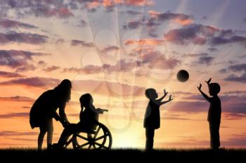 Disabled child in wheelchair crying and his mother near children play with ball sunset. Concept disabled child