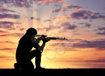 Silhouette of a terrorist with a weapon against a background of a sunset