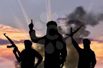 Silhouette of three terrorists with weapons dictate their terms at sunset