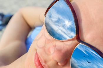 Concept of vacation. Reflection of the sky beautiful woman in glasses close-up. design element