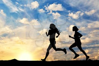 Concept of sport. Silhouette of two girls running competition at sunset