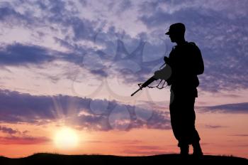 Silhouette of soldier with a gun on a background of sunset