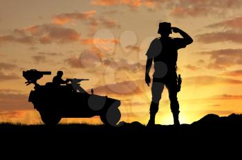 Silhouette of a soldier and a combat vehicle Humvee at sunset