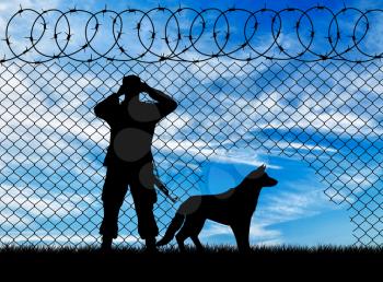 Concept of the refugees. Silhouette of a border guard and a dog near the hole in the fence