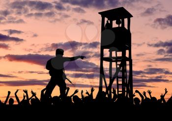 Concept of security. Silhouette of a military border guard on the background of the crowd of refugees and the watchtower
